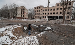 A man stands inside a shell crater in the aftermath of an overnight shelling on a military facility in Brovary near Kiev