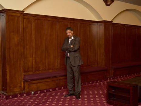 man in a suit posing against a panelled wall
