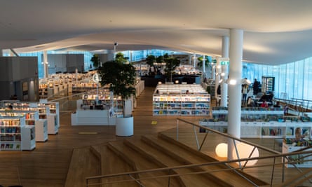 Modern interior of Helsinki Central Library Oodi with tall glass windows, wooden flooring and rows of low bookshelves