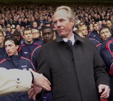 Sven-Göran Eriksson in front of a crowd of supporters at a football match, shaking the hand of an unseen fan