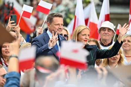 Rafał and Małgorzata wave at people in a sea of red and white Polish flags