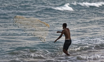 A Somali fisherman casts his nets at dusk on the beach
