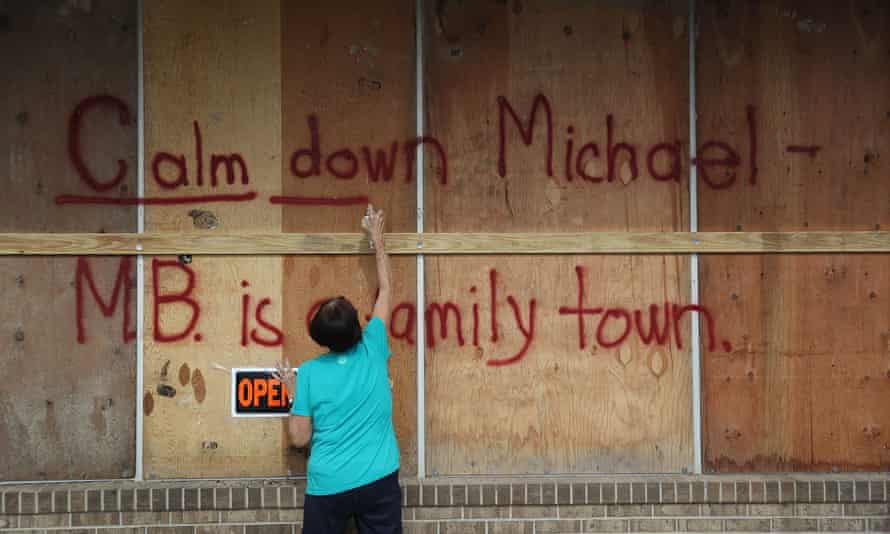 A woman spray paints the words “Calm down Michael” on the plywood over her daughter’s business in preparation for the arrival of Hurricane Michael in Mexico Beach, Florida.