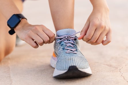 Close-up view of female jogger hands tying laces of her sport shoes