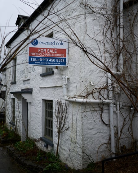 The side of the white walled pub, with a for sale sign