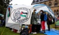 Students from the University of Oxford stand next to a tent with an “Oxford Action for Palestine” banner.