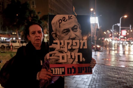 An Israeli activist holds a photo of Benjamin Netanyahu that reads in Hebrew: “Guilty, abandoning life, we deserve more.”