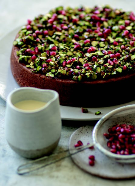 Pistachio and lime syrup sponge decorated with chopped pistachios and pomegranate seeds, with a small jug of cream. 