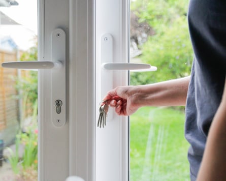 A hand holding keys locking a patio door.