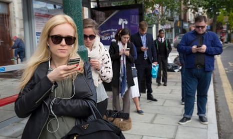 People looking at their mobile phones while waiting for the bus 
