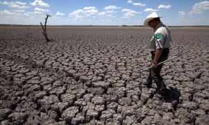 Texas State Park police officer Thomas Bigham walks across the cracked lake bed of O.C. Fisher Lake Wednesday, Aug. 3, 2011, in San Angelo, Texas. Heat and drought dried up the lake that once spanned over 5400 acres.