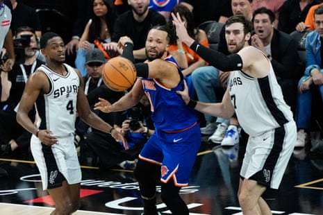 The Knicks' Jalen Brunson makes a pass as the Spurs' Luke Kornet and De'Aaron Fox look on during the first half.