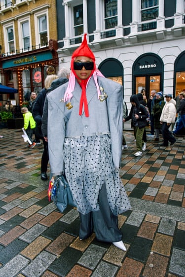 A person with a red hat and an oversized grey jacket