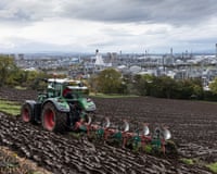A farm worker plows fields overlooking Grangemouth petrochemical and refining plant in Scotland.