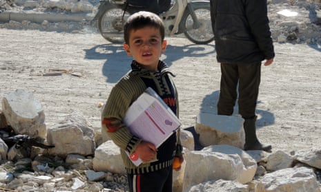A Syrian boy holds his books as he stands outside his school following airstrikes by Syrian government forces in the northern Syrian city of Marea, on the outskirts of Aleppo, in 2013.
