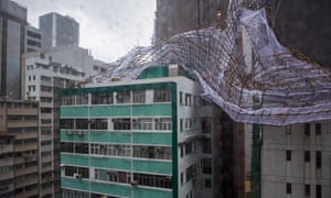 Rescue workers attempt to secure bamboo scaffolding that was damaged overnight at the top of a building in Hong Kong during Typhoon Nida.
