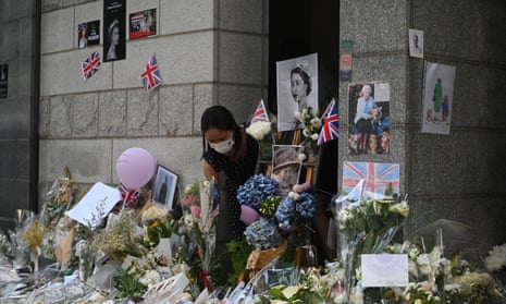 A woman lays flowers outside the British consulate where Hong Kong residents have been gathering to mourn the death of Queen Elizabeth II.