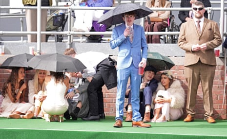 Racegoers shield themselves from the rain on Grand National day.