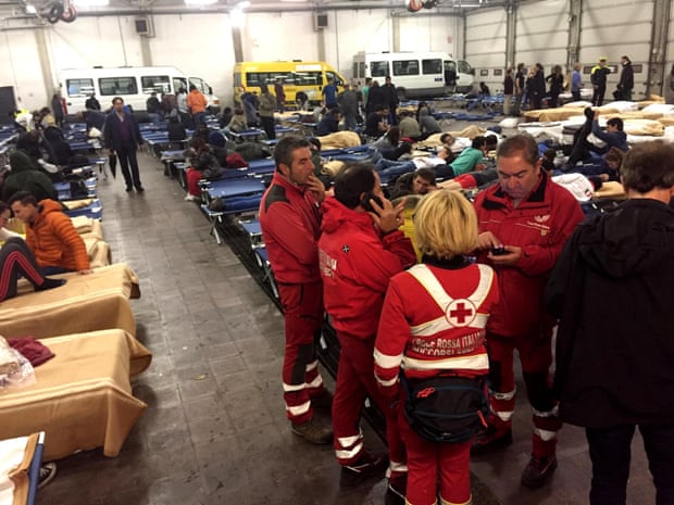 Rescuers assist people sheltering in a bus hangar in Camerino.
