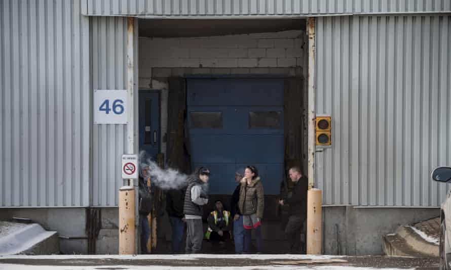 Workers take a smoke break on their last day outside the GM plant in Oshawa, Ontario, on 18 December.