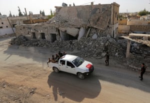 Free Syrian Army fighters ride on a pickup truck decorated with a Turkish flag past damaged buildings in the rebel-held town of al-Rai, in Aleppo governorate