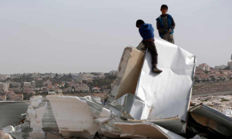 Palestinian Bedouin boys climb on the remains of their makeshift homes near al-Azariya, on the West Bank. The Israeli army said it demolished the homes as they were built illegally. The illegal Jewish settlement of Maale Adumin is seen in the background. 