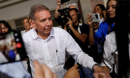 Edmundo González makes his way through a crowd of people filming him on phones and with cameras