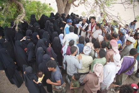 Large crowd of men and women around a group of aid workers
