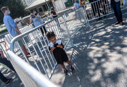 Uma criança fica perto de uma barreira de metal, olhando para o celular em suas mãos