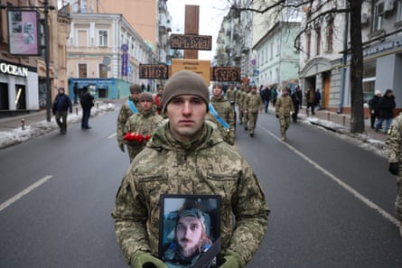 A soldier carries a portrait of Maksym Kryvtsov, a Ukrainian poet killed in action on 7 January 2024 aged 33.