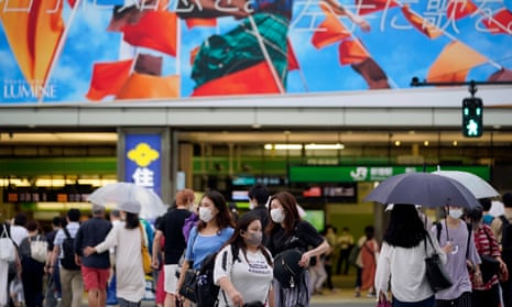Pedestrians wearing face masks in front of Shinjuku station in Tokyo
