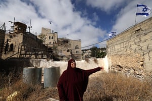 A woman, upset and alone, next to a wall with Israeli flags