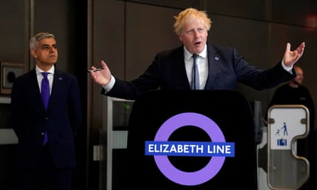 Boris Johnson waves his arms behind a podium with the Elizabeth line sign.