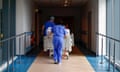 Medical staff push a patient on a hospital bed along a corridor