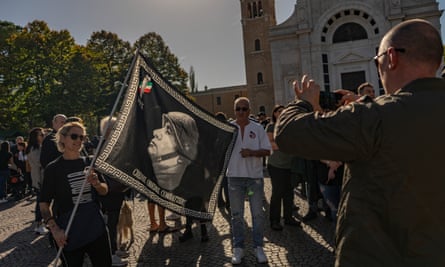 A woman holds a flag with an image of Mussolini in Predappio