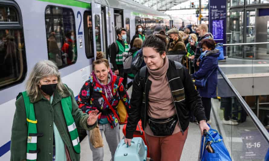 Volunteers with green jackets provide assistance to Ukrainians fleeing the war as they disembark from a train from Warsaw at Hauptbahnhof main railway station in Berlin.