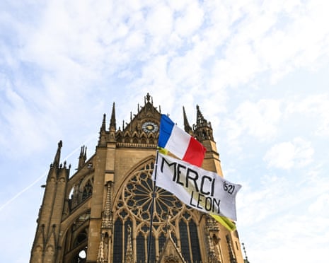 A person waves a French national flag and a banner reading in French "Thanks Leo" as it waits outside the Saint-Etienne Cathedral in Metz, northeastern France.