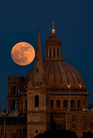 La luna de fresa se eleva detrás de la catedral anglicana de San Pablo y la basílica de Nuestra Señora del Monte Carmelo en La Valeta, Malta.