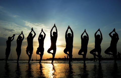 People doing yoga at beach against sky