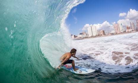 a surfer rides a summer cyclone wave at New Pier beach, Durban.