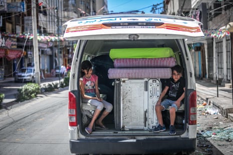 Palestinian children sit in the back of a van loaded with salvaged belongings from their home at the al-Jawhara Tower in Gaza City, which was heavily damaged in Israeli airstrikes.