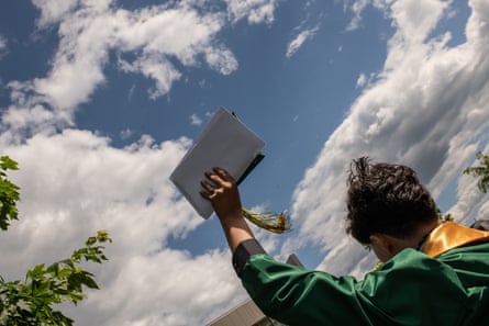 a young man holding his cap in the air