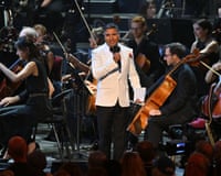 Presenter Nick Mohammed speaks into a microphone on stage at the Proms