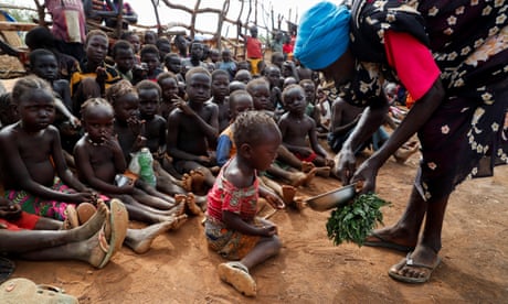 Niños africanos con aspecto hambriento son alimentados con hojas hervidas en Sudán, un país devastado por la guerra.