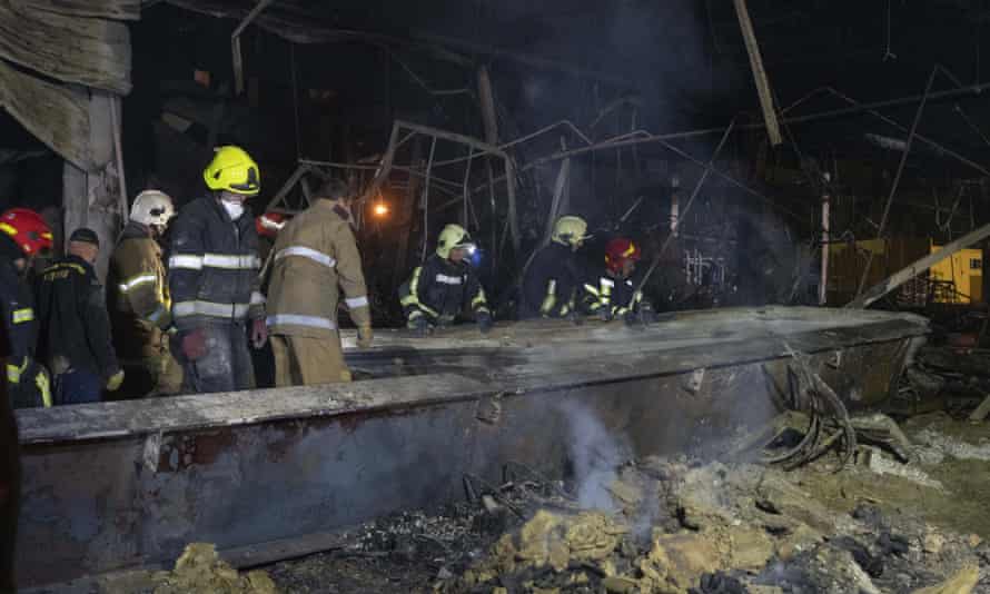 Ukrainian State Emergency Service firefighters take away debris at a shopping centre burned after a rocket attack in Kremenchuk, Ukraine, early Tuesday.