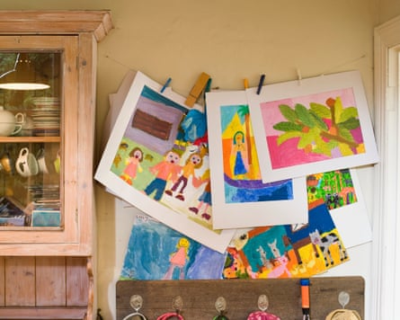 Children’s paintings hung up on a wall by a cabinet