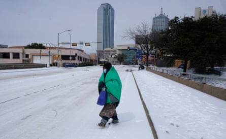 A woman wrapped in a blanket crosses the street near downtown Dallas on Tuesday.