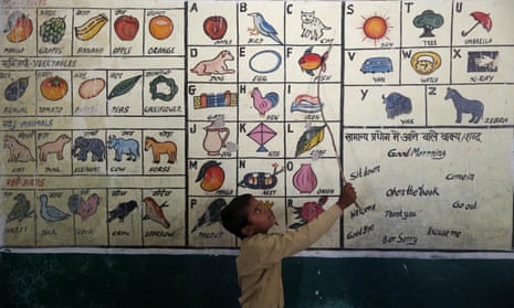 A schoolboy reads from illustrations painted on a wall in a school in Allahabad, India. 