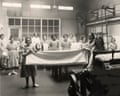 Women working in a Magdalene Laundry, holding fabric in industrial setting, circa 1940s.