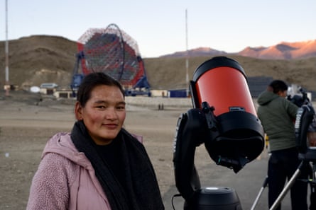 Tsering Dolkar standing next to a telescope with mountains in the background.